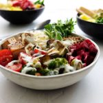 Tigela vegana colorida com vegetais frescos e outros ingredientes de origem vegetal.