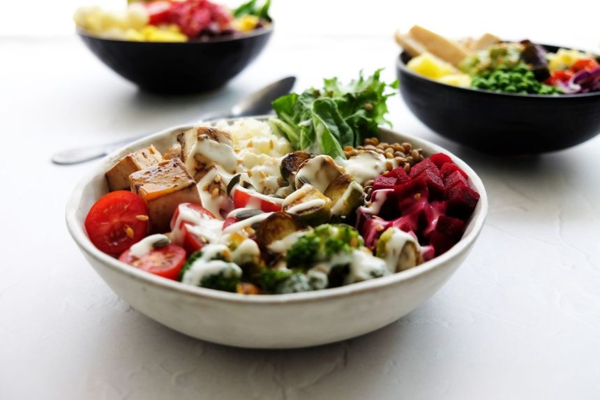 Tigela vegana colorida com vegetais frescos e outros ingredientes de origem vegetal.