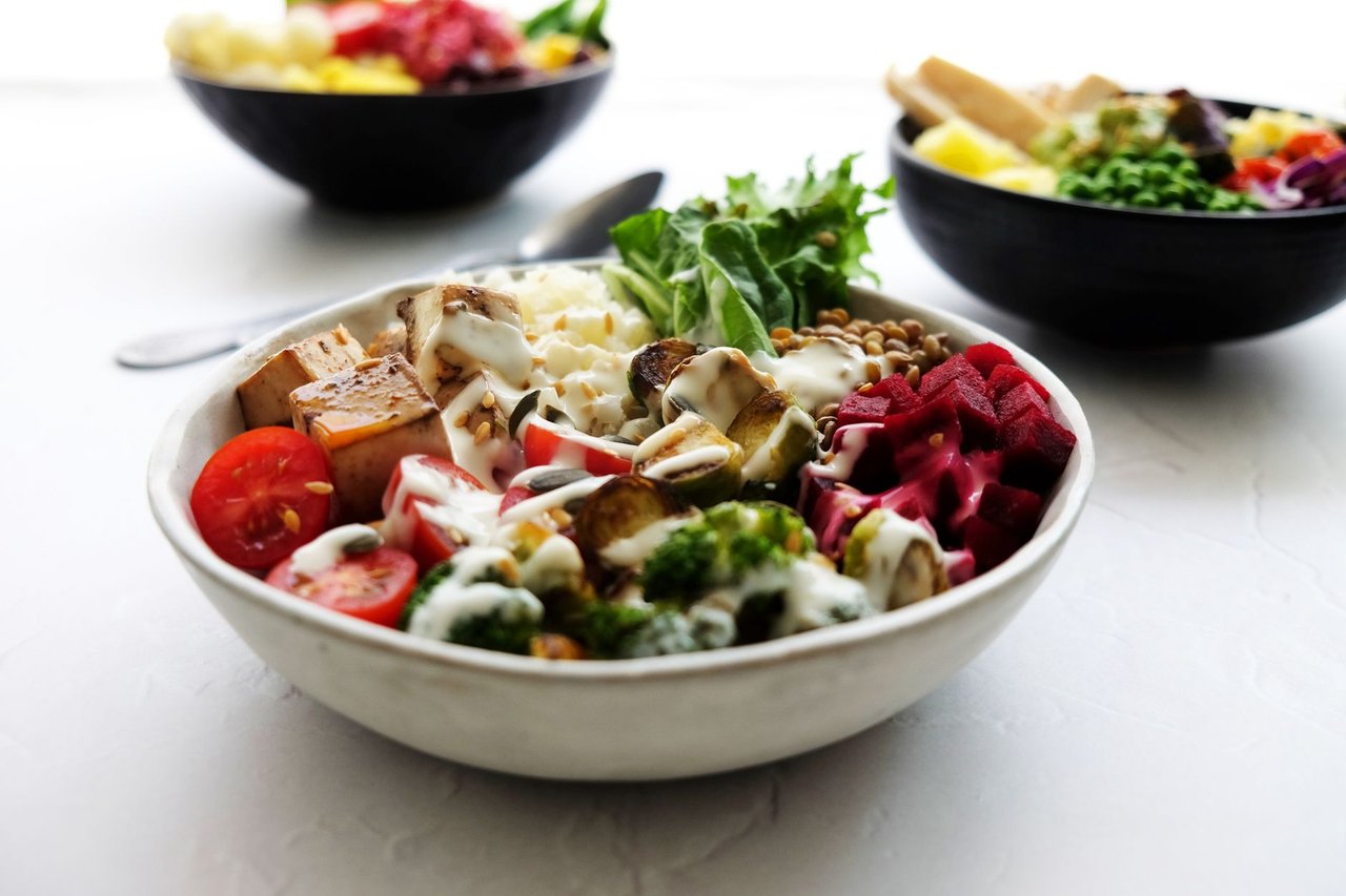 Tigela vegana colorida com vegetais frescos e outros ingredientes de origem vegetal.