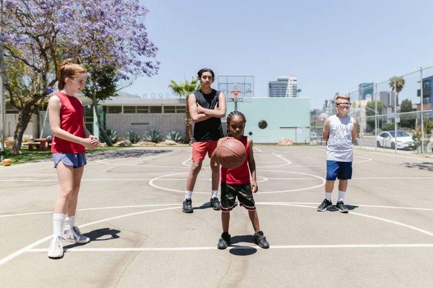 Grupo diverso de adolescentes reunido em uma quadra de basquete ao ar livre durante uma atividade recreativa