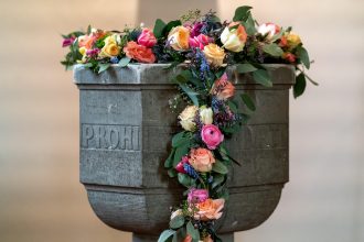 Pia batismal decorada com flores no interior de uma capela cristã